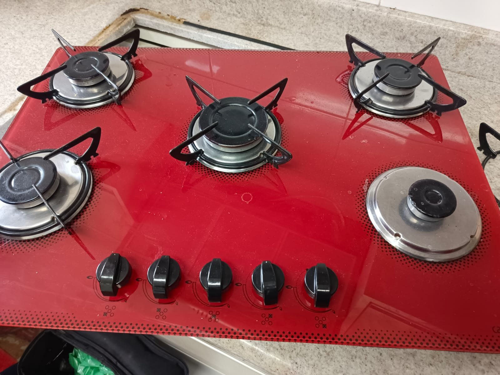 Cooktop a gás de vidro vermelho fotografado no acervo de atendimentos.